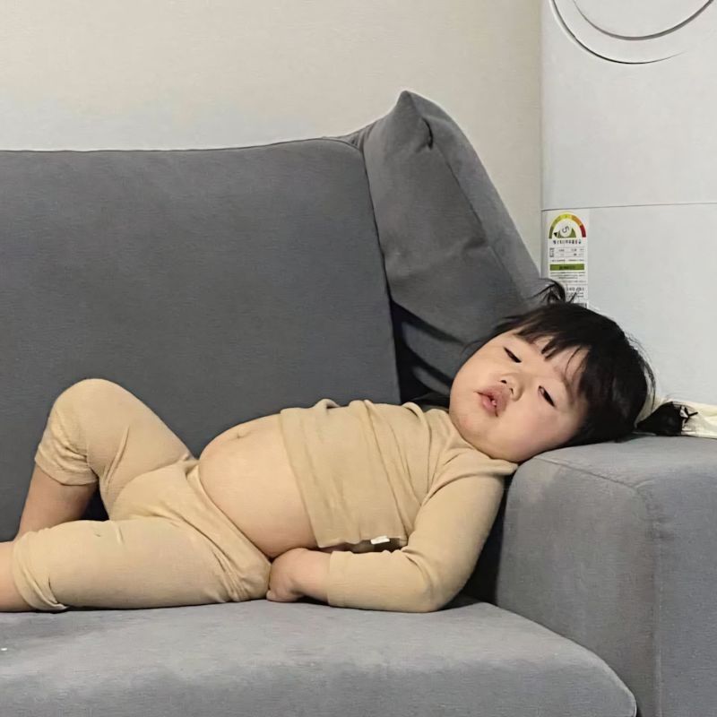 em bé bụng phệ nằm ườn ra ghế sofa, mắt lờ đờ uể oải buồn ngủ