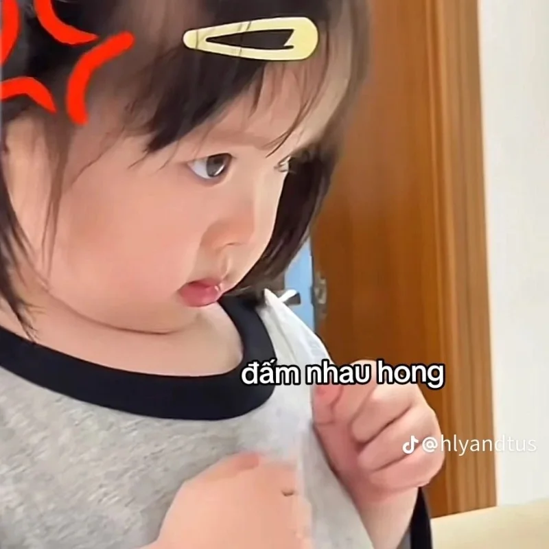 Meme đấm em bé đáng yêu giơ nắm đấm đe dọa trong phòng ngủ.