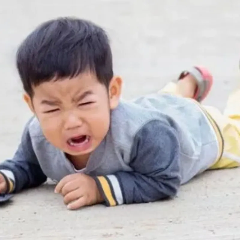 Bé trai nằm sấp ngoài đường đang nhắm mắt khóc nức nở
