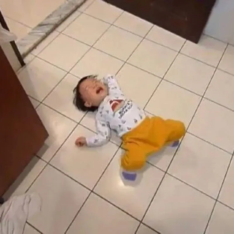 Meme em bé nằm khóc lóc giãy đành đạch trên sàn gạch