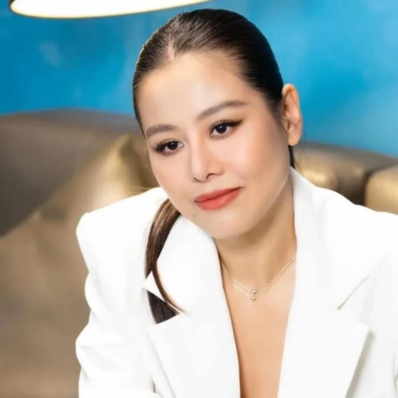Meme Nam Thư mặc vest trắng, ánh mắt nhìn nghiêng đầy ẩn ý, môi cười nhẹ