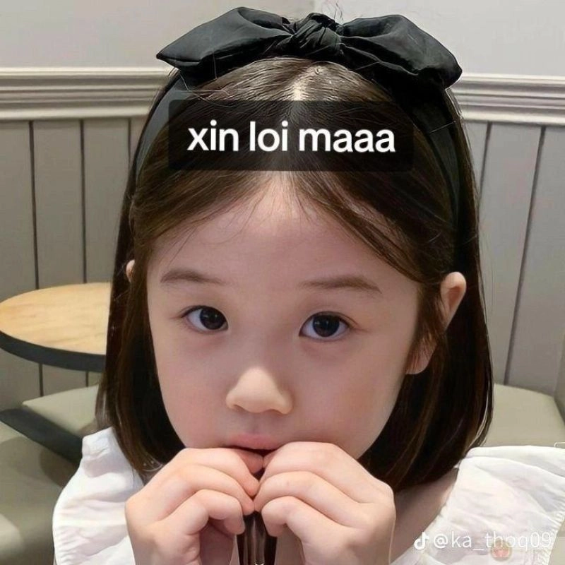 Hình em bé đeo nơ đen bặm môi đầy ăn năn
