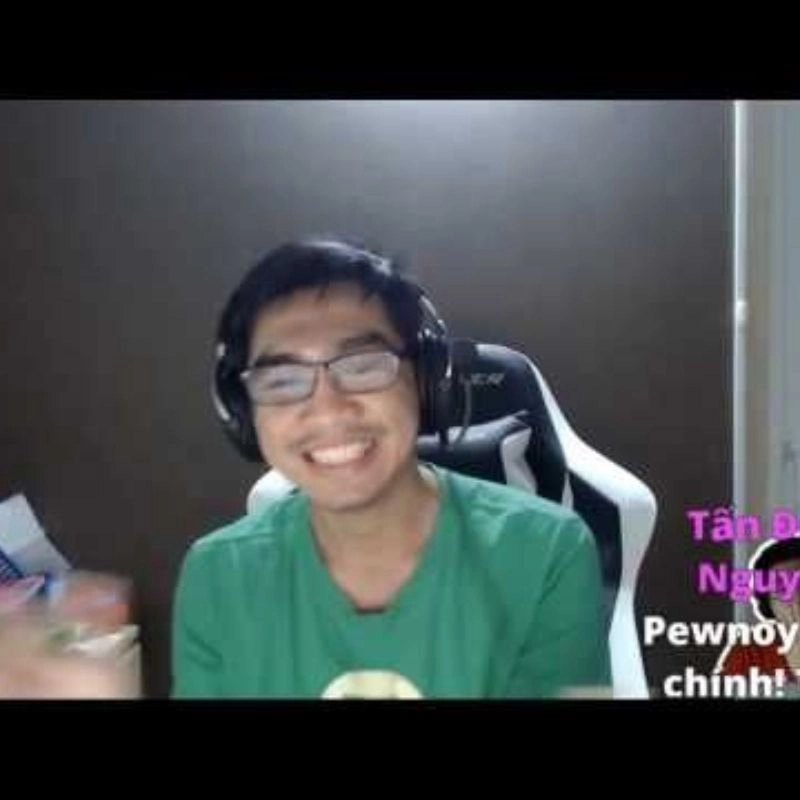 Streamer PewPew mặc áo phông xanh cười tươi trên sóng livestream