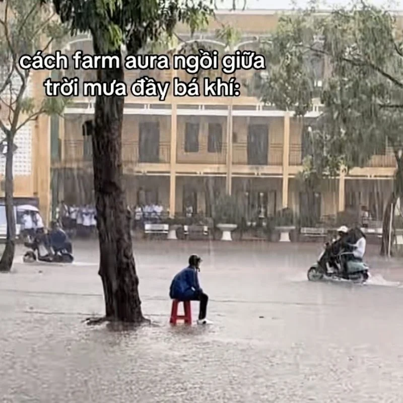 Hình ảnh một bạn học sinh ngồi giữa sân trường ngập nước mưa lầy lội