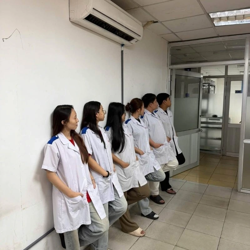 Các bạn sinh viên ngành y mặc áo blouse trắng đứng dựa tường nối tiếp nhau