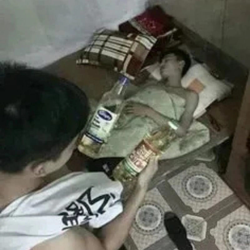 Ảnh meme thanh niên cầm hai chai dầu ăn đứng nhìn bạn mình đang ngủ trên giường