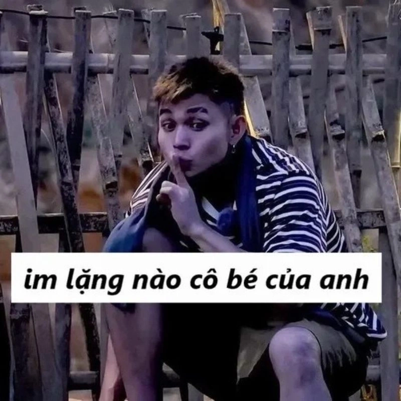 Ảnh chế rapper Bray ngồi bên hàng rào tre đưa ngón tay lên môi bảo im lặng