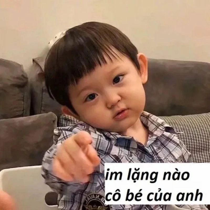 Em bé trai tóc mái ngố mặc áo caro chỉ tay thẳng vào màn hình dặn im lặng