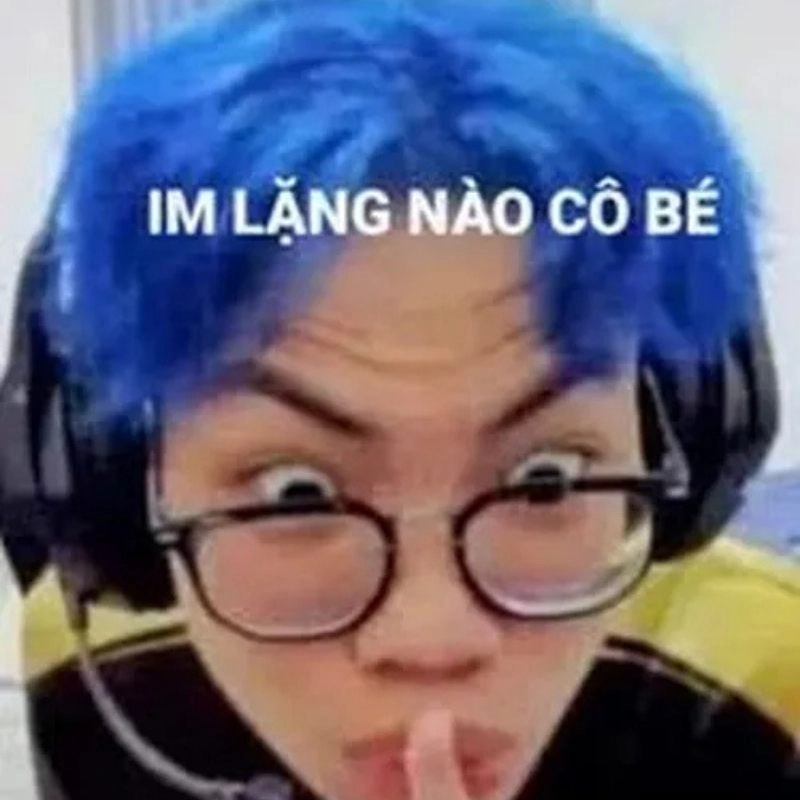 Streamer tóc xanh đeo kính trợn mắt áp ngón tay lên môi nhắc im lặng